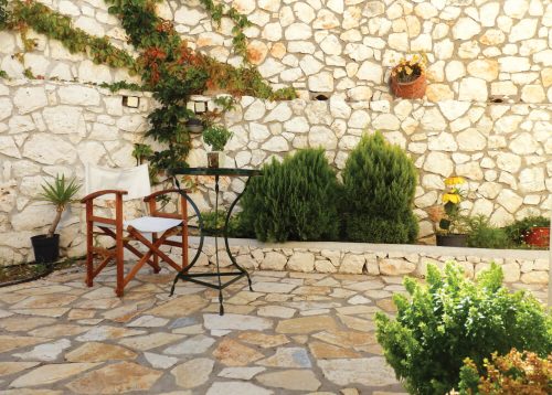Πέτρινος πλακόστρωτος κήπος με τραπεζάκι και καρέκλα σκηνοθέτη στη Natura Villas Λευκάδας